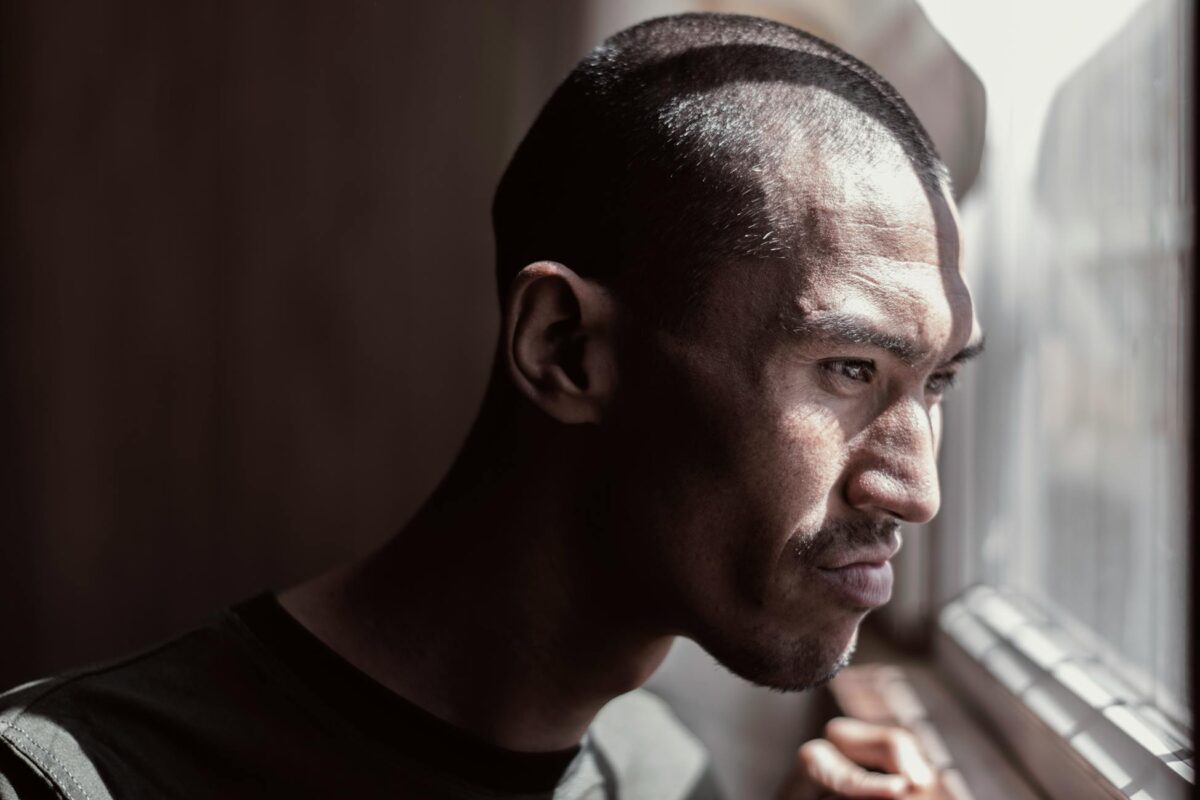 Portrait of a contemplative man looking out the window, bathed in natural light.