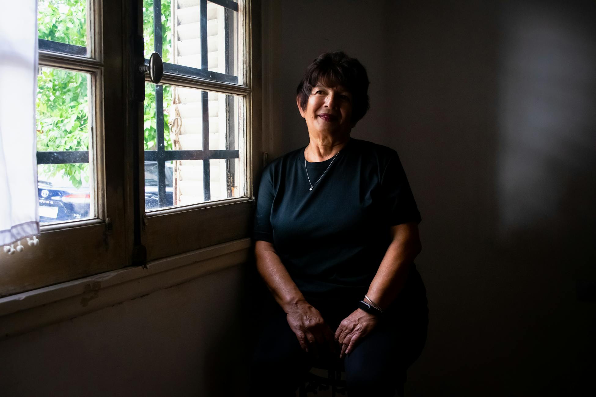 Portrait of a senior woman sitting by a window with natural light entering the room.