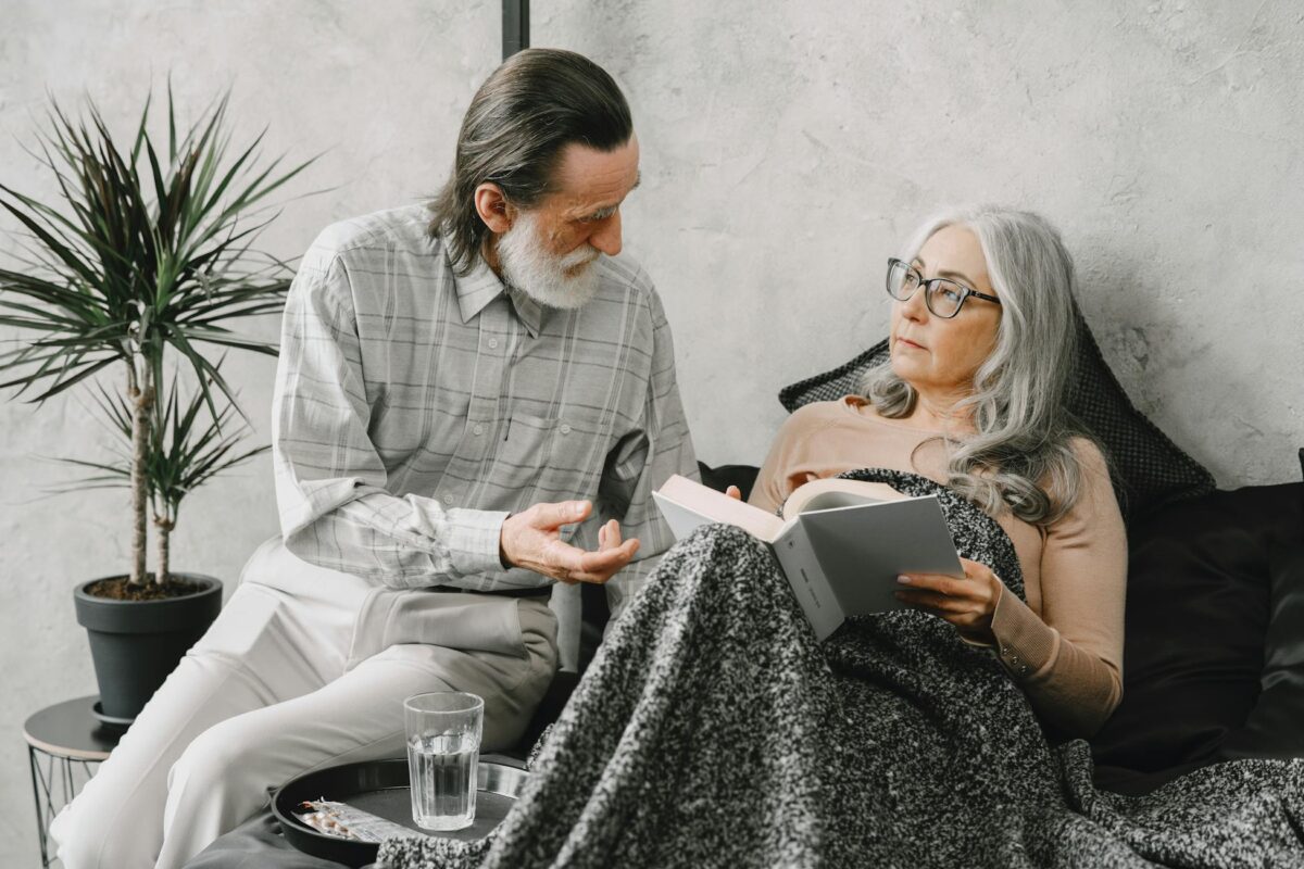 An elderly couple enjoys a peaceful moment reading together indoors, illustrating love and companionship.