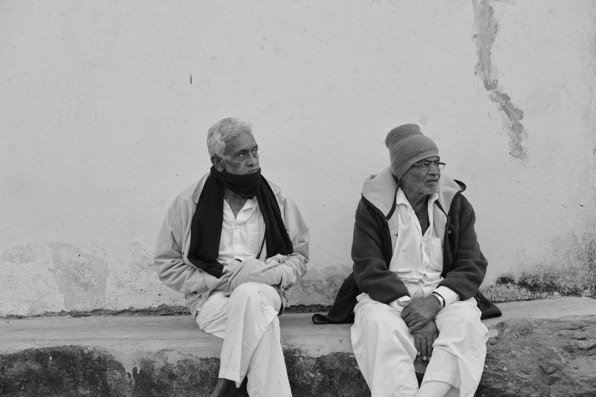 Black and white photo of two elderly men sitting on a bench, reflecting contemplation.