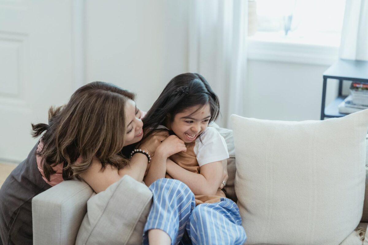 Joyful mother and daughter embracing and laughing at home.