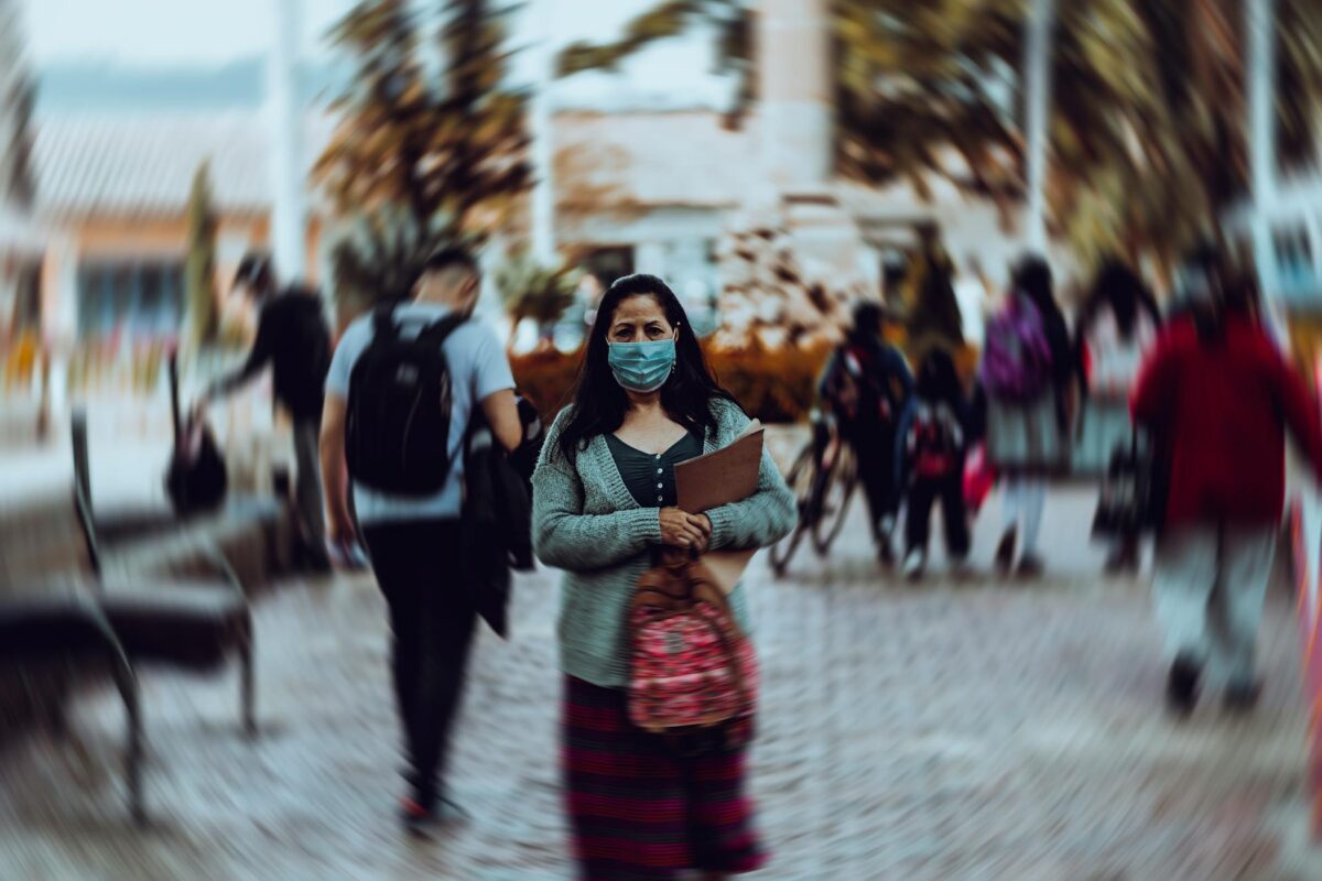 A woman in a face mask stands on a bustling street in Bogotá, capturing the new normal during the pandemic.
