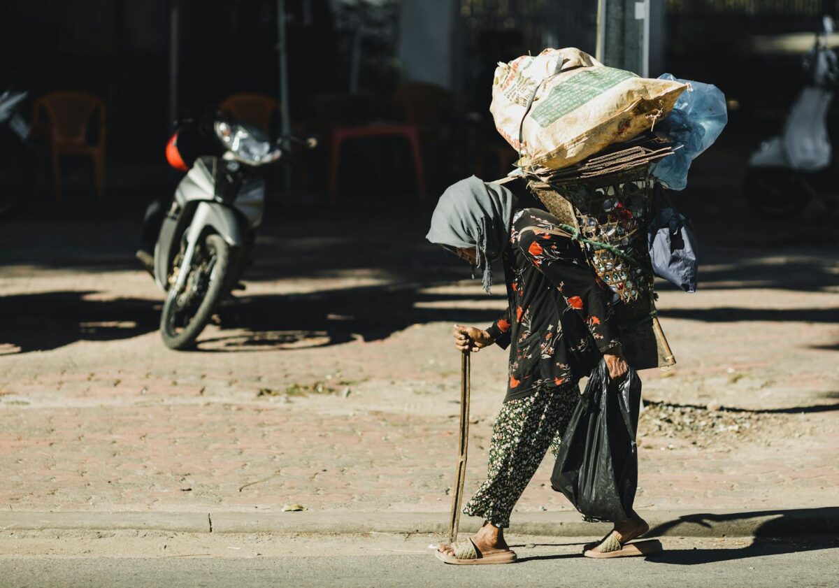 An elderly woman carries a heavy load on her back in Kon Tum, Vietnam, showcasing resilience.