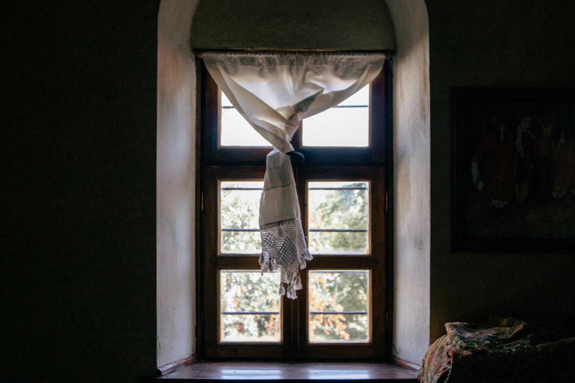Charming window with sunlight streaming through vintage curtains in Elazığ, Türkiye.