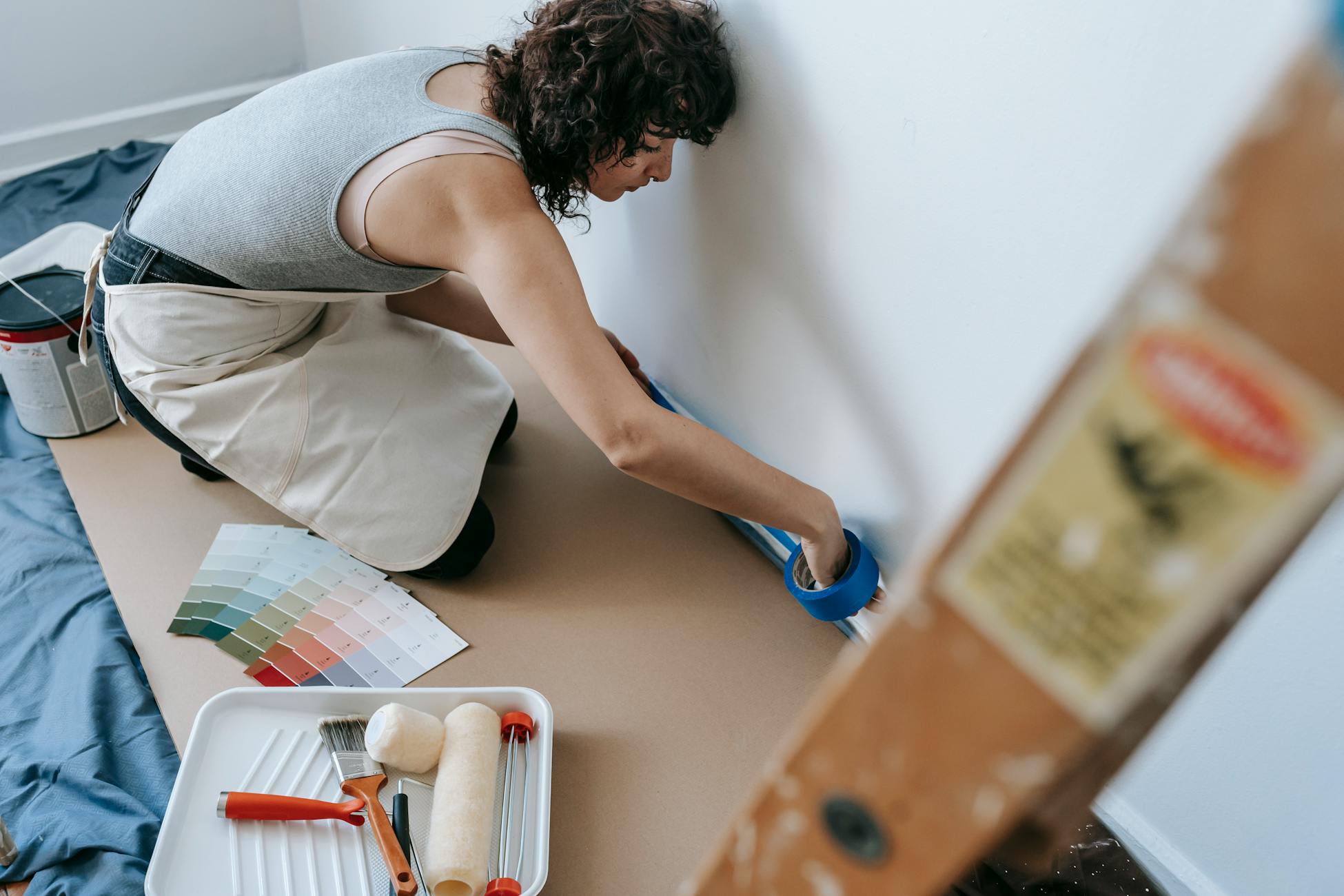 Female using blue tape for home painting project in a modern apartment.