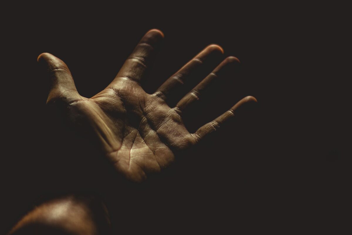 A powerful silhouette of an outstretched palm against a dark background, evoking emotion.