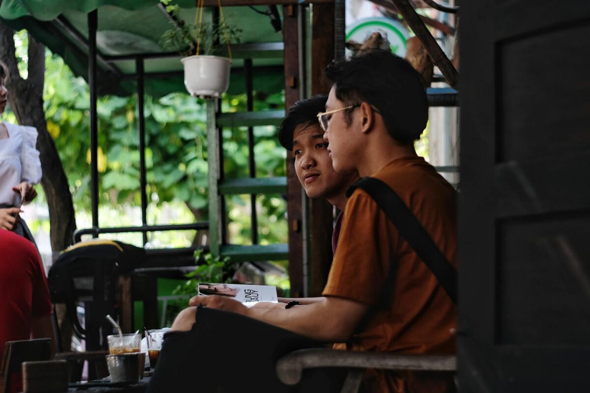 Two men conversing at an outdoor café, enjoying a relaxed ambiance with drinks.