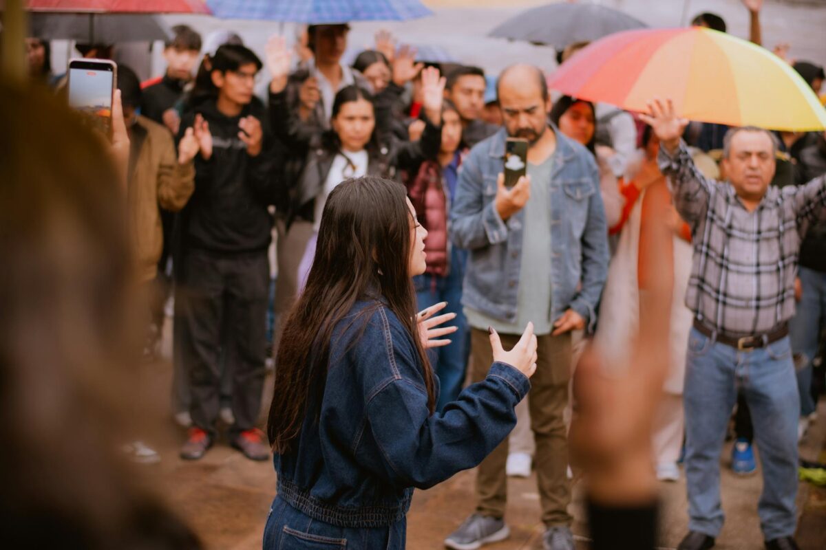 A lively outdoor event with diverse attendees, colorful umbrellas, and engaged atmosphere.