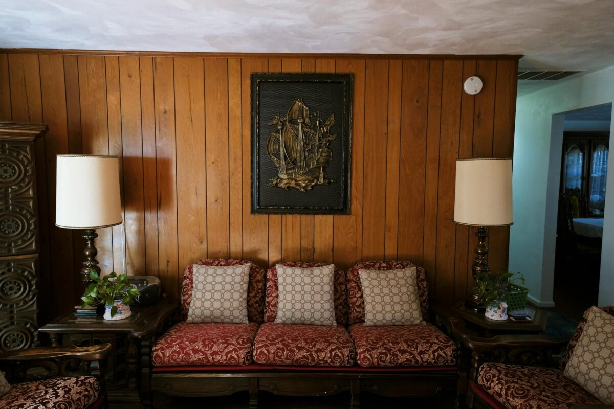 Warm living room with vintage furniture and wood paneling, showcasing classic decor.