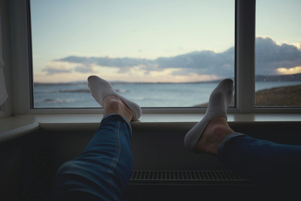 Scene of person relaxing by a window, enjoying a serene ocean view.