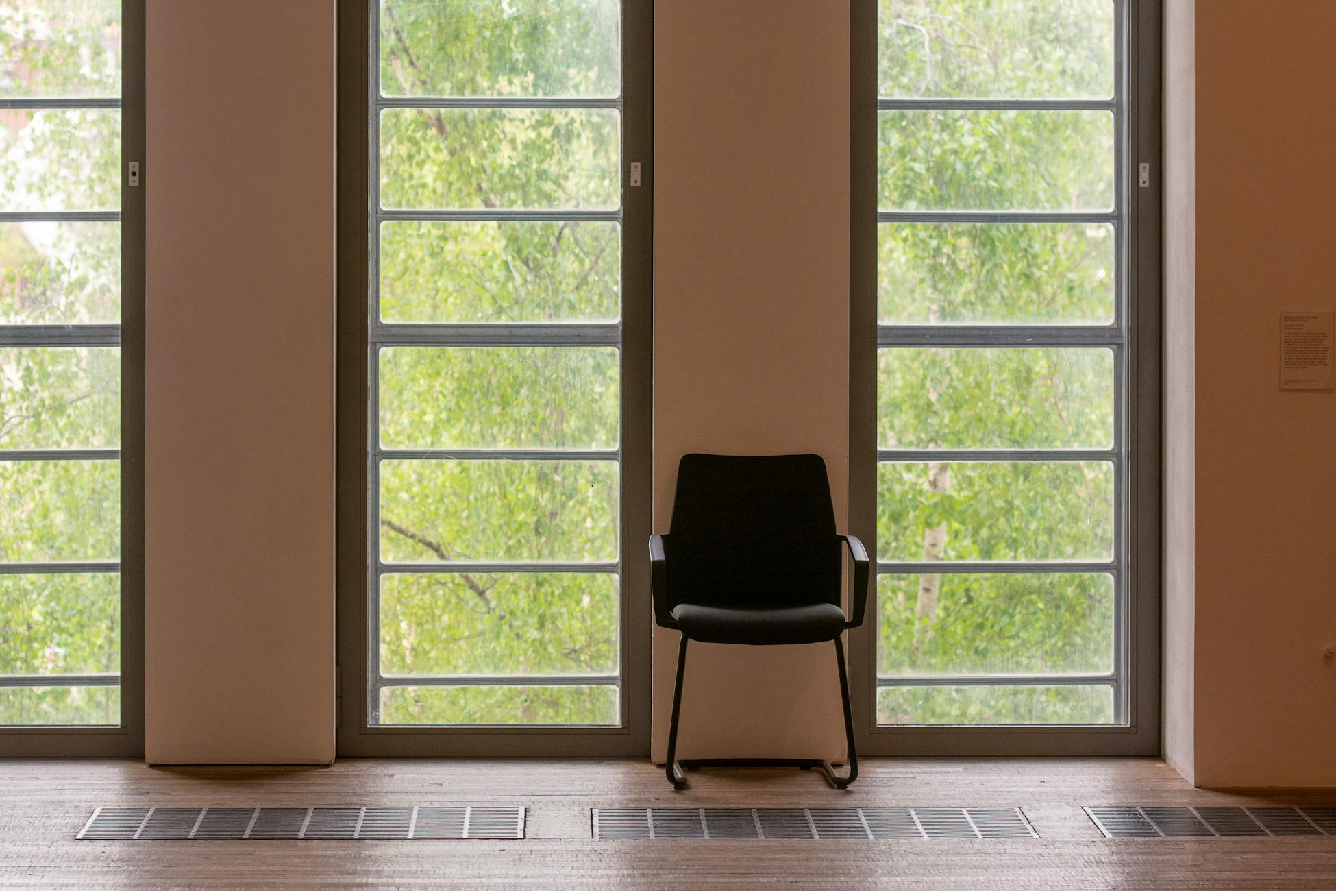 A single chair in a minimalist room with large windows and natural light.