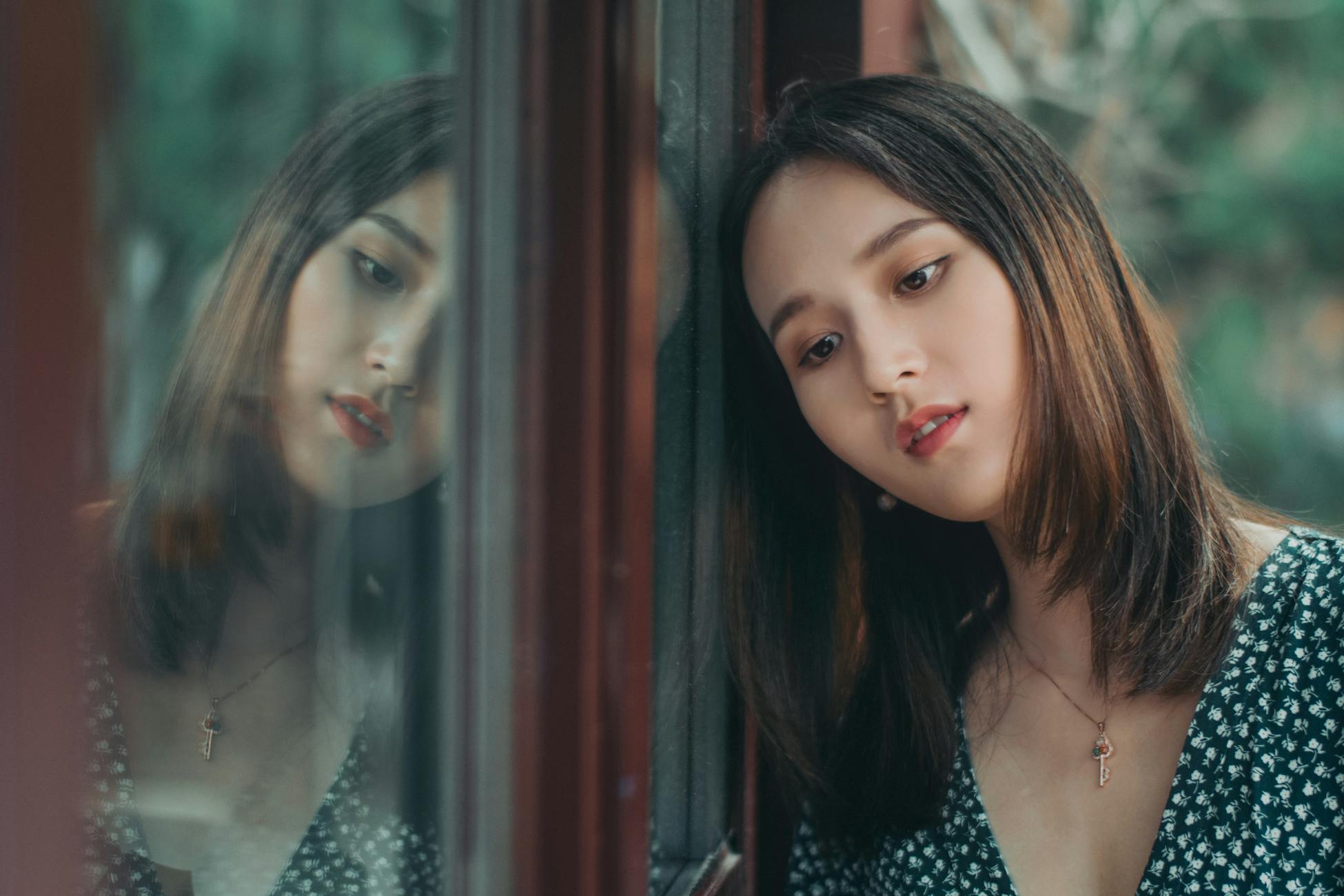 Portrait of a thoughtful woman leaning on a window, reflecting deep contemplation.