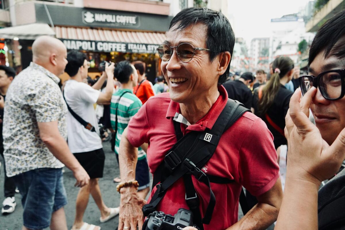 A joyful street scene with a smiling photographer during a lively festival.